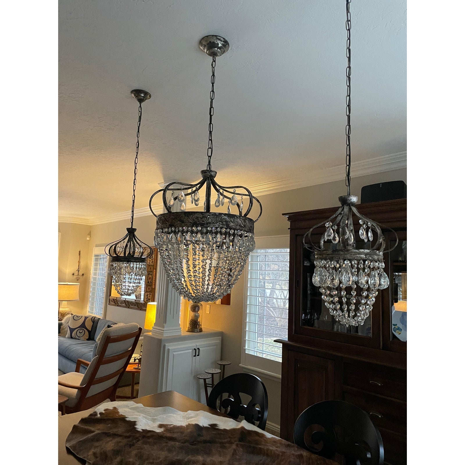 Vantara large chandelier antique gold above a long dining table, wide shot