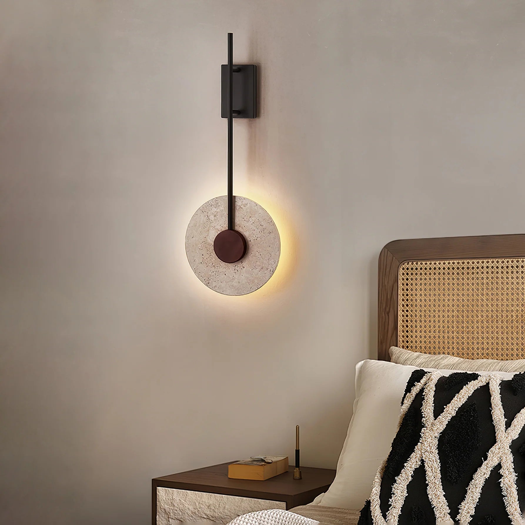 Side profile of the Tovi travertine disc wall sconce showing hardwired installation