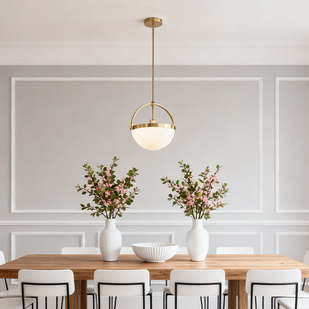 Gold and white pendant lights used as accent lighting above a long dining table with panelled walls