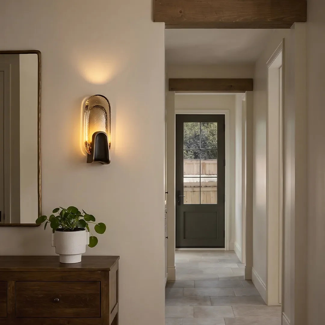 Oval art deco glass wall sconce in a modern hallway, brass wall light with textured shade