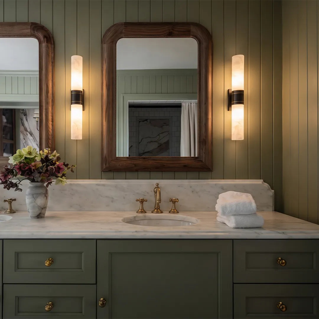 Niva marble wall sconce installed beside a bathroom mirror, warm ambient lighting