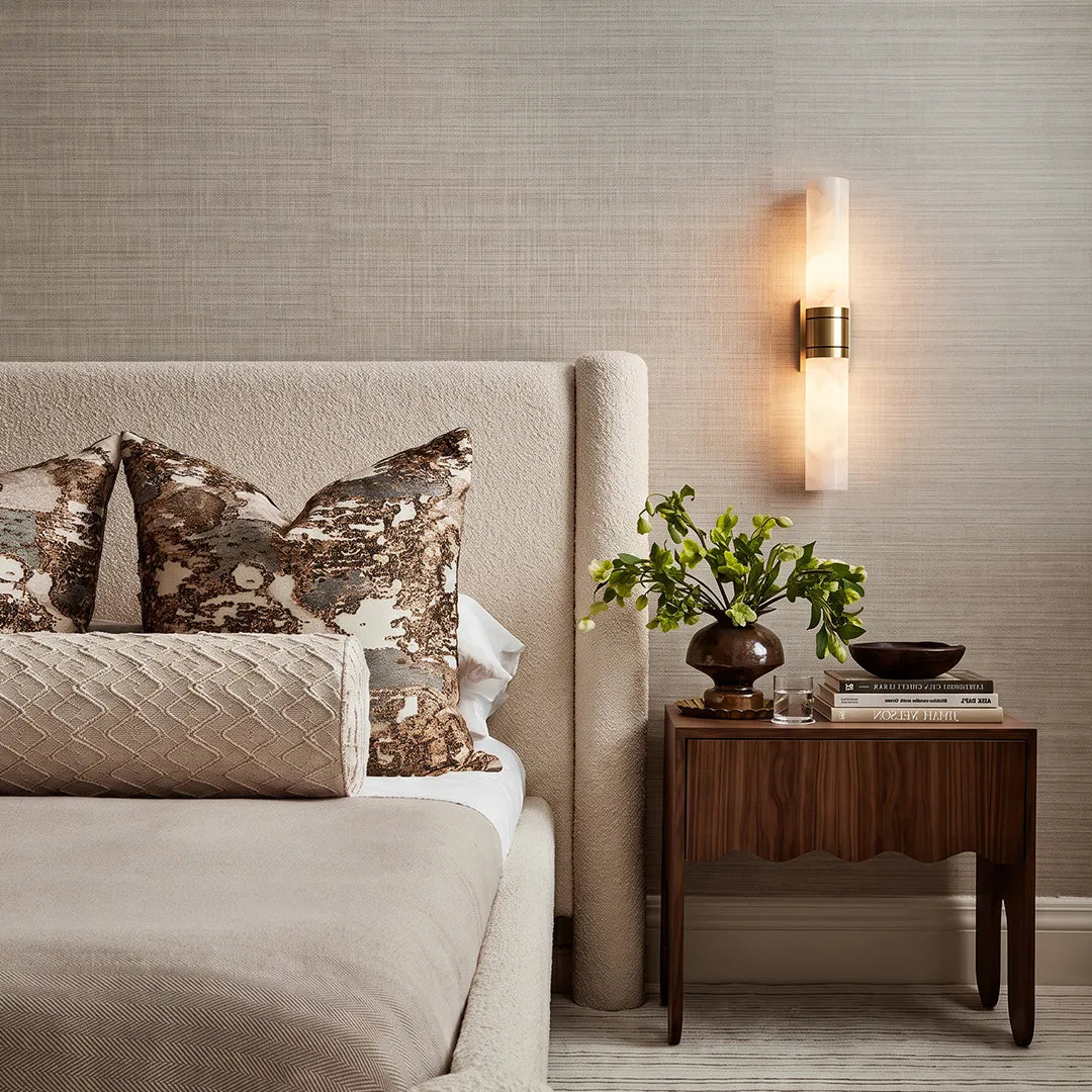 Niva marble wall sconce in a bedroom interior, vertical cylindrical stone shade illuminated