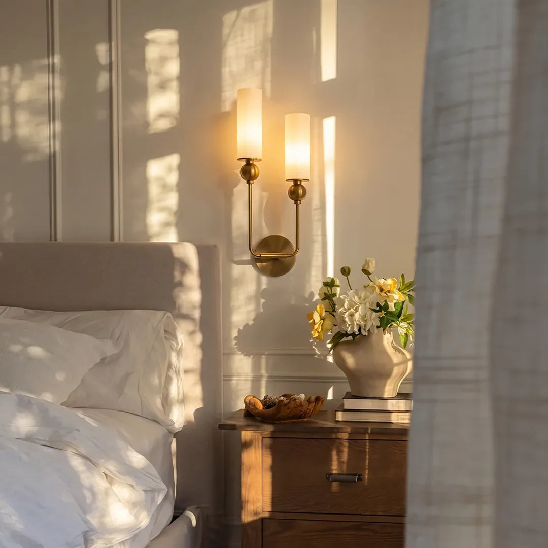 Niva double brass wall sconce mounted beside a bed as bedside lighting