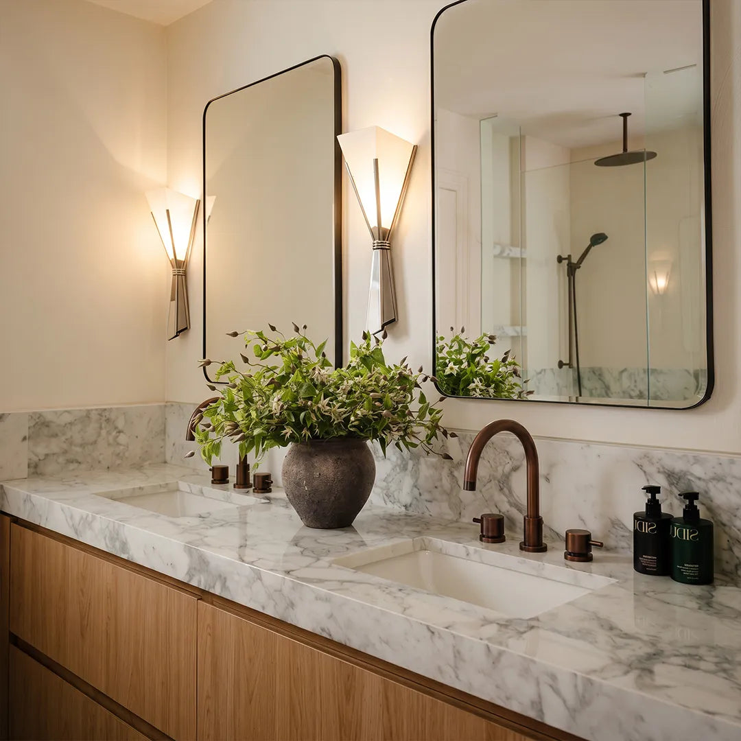 Niva marble wall sconce mounted beside a bathroom mirror as vanity lighting