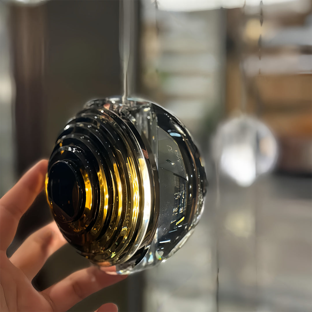 Hand holding an Aureon smoked glass sphere pendant light, showing scale and design