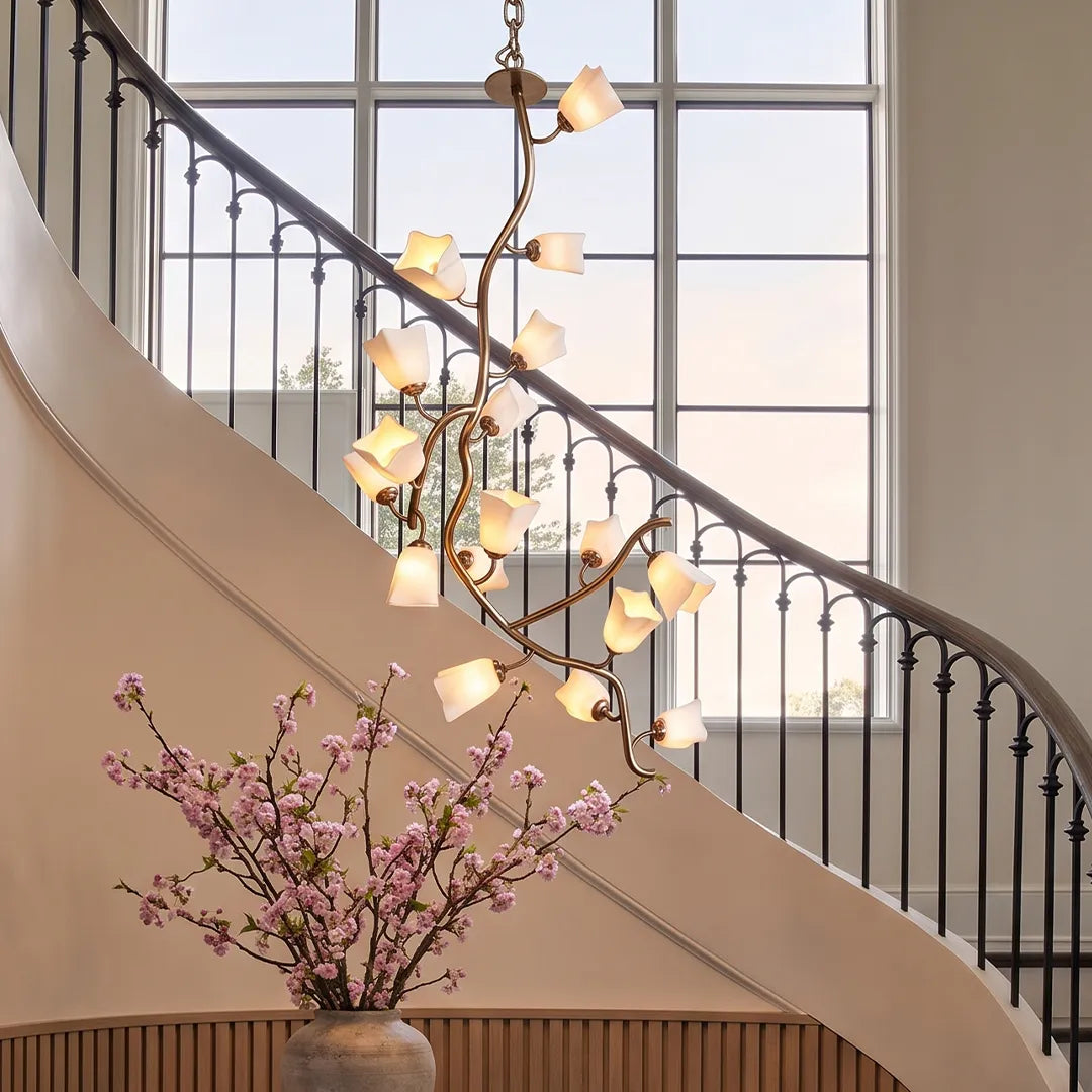 Modern glass branch chandelier installed in a curved staircase foyer