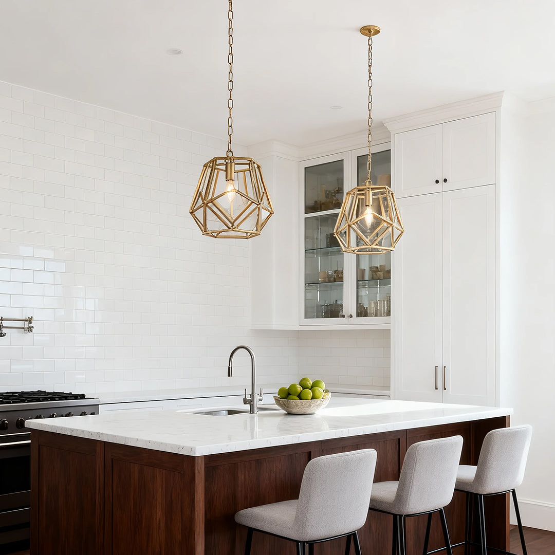 Gold geometric pendant light above a kitchen island with white cabinets