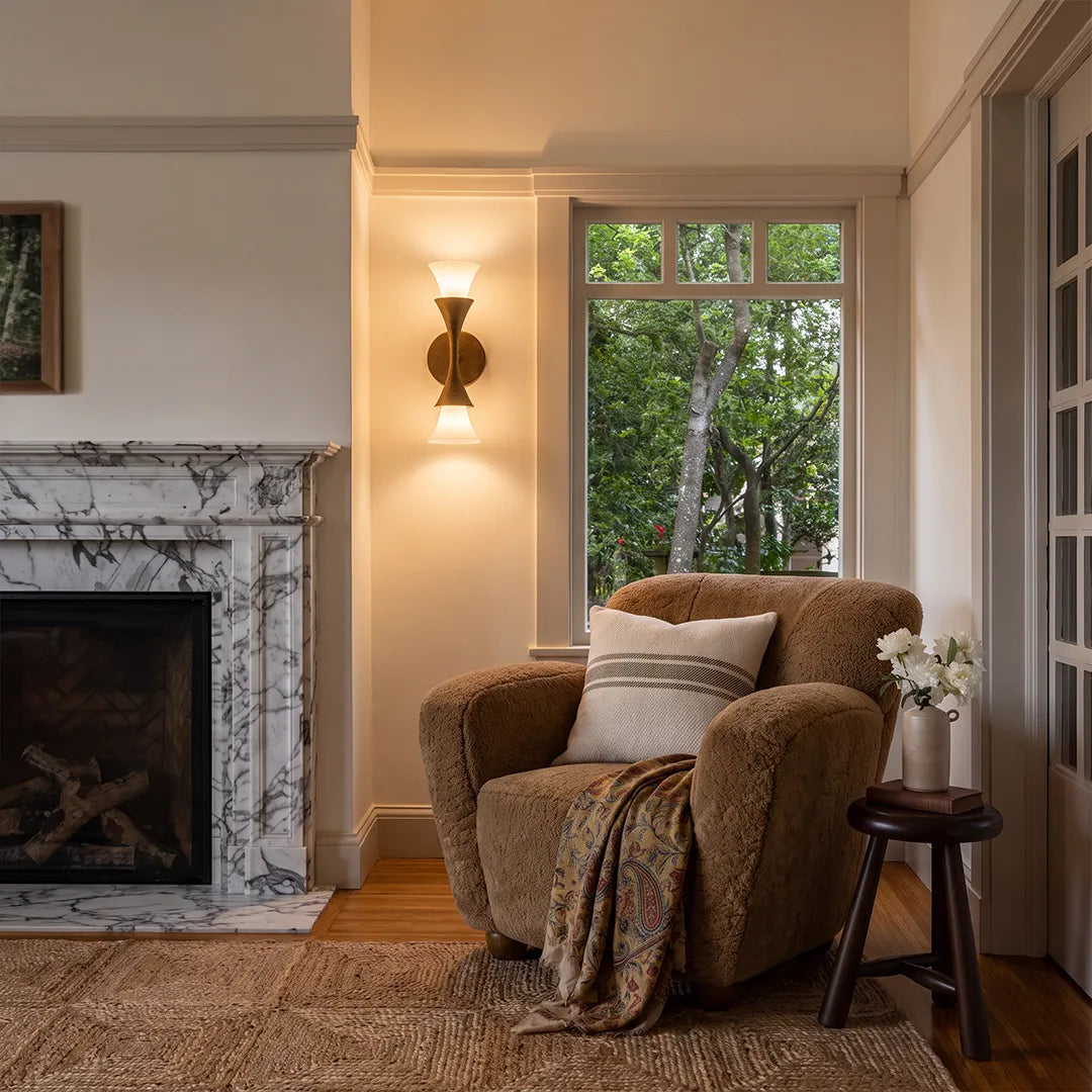 Niva brass wall light mounted beside a fireplace in a seating area