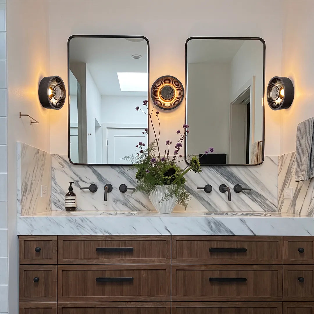 Pair of Niva round wall sconces mounted either side of a bathroom vanity mirror