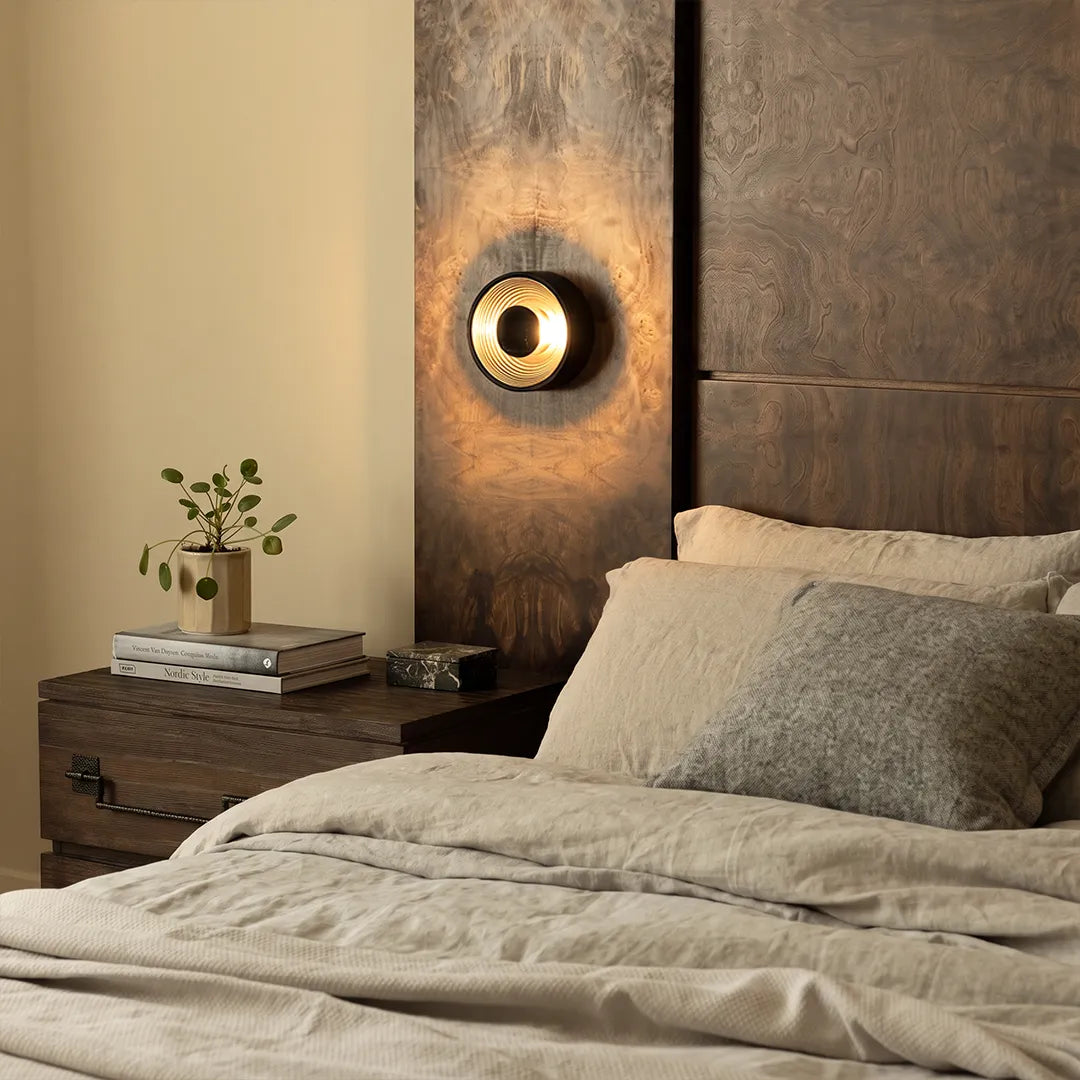 Niva wall sconce glowing on a bedside accent wall in a modern bedroom interior