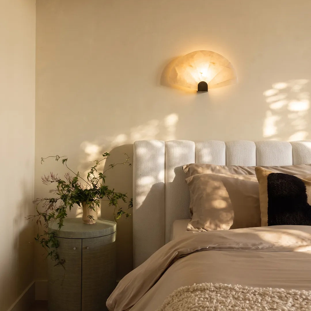 Marble wall sconce beside a bedside nightstand, soft stone light in a contemporary bedroom