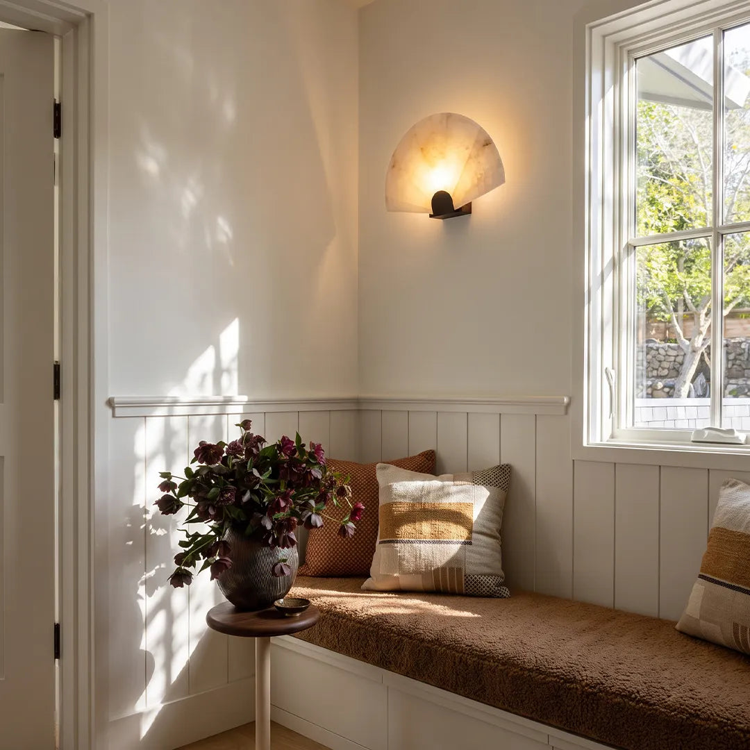 Niva marble wall sconce beside a window seat, providing soft ambient light in a living space