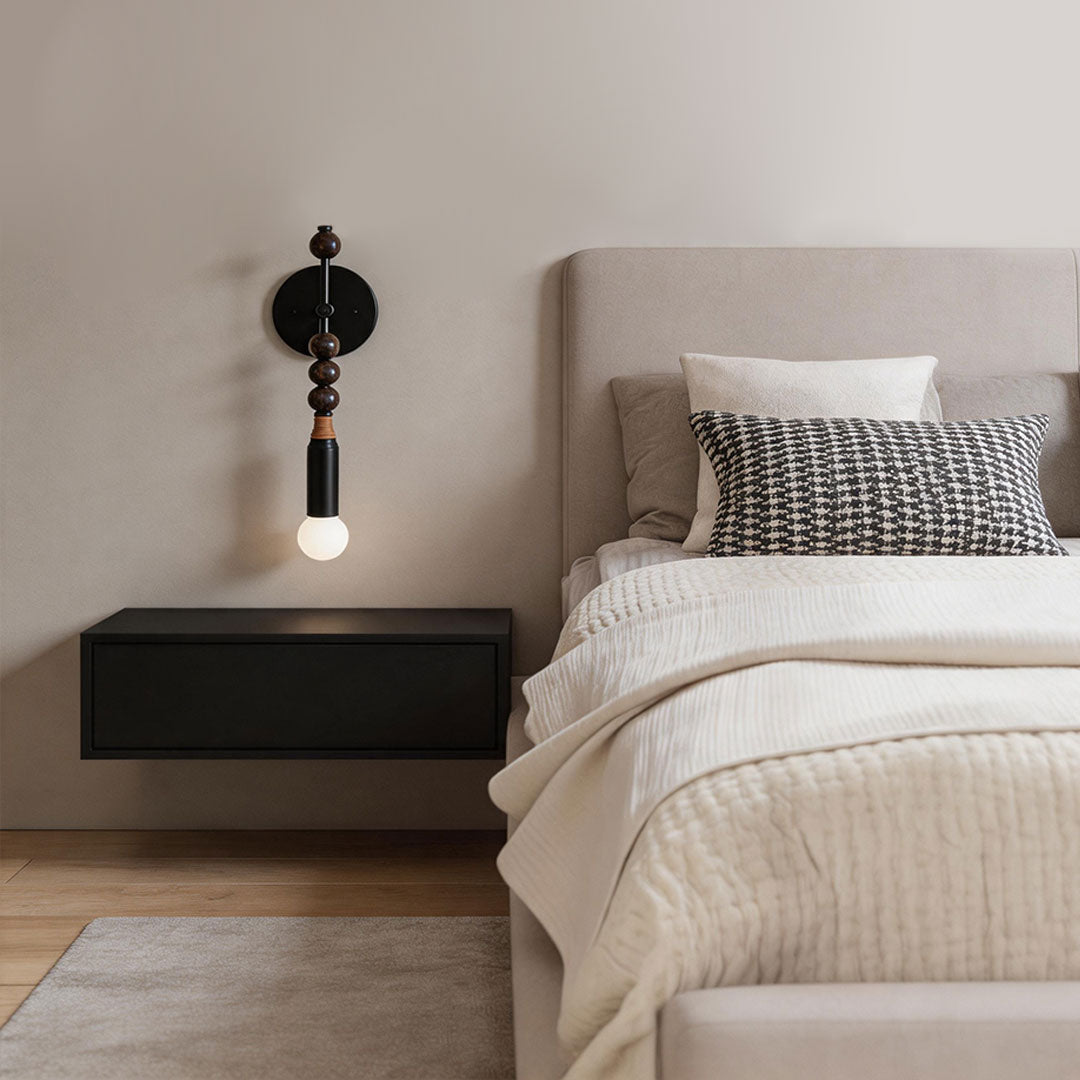 Alure globe wall sconce installed in a modern bedroom above a bedside table, warm ambient lighting