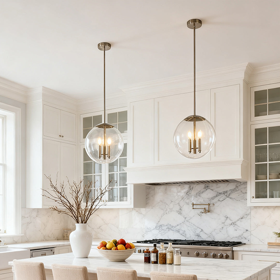 Two Aureon clear glass orb pendant lights hung above a white marble kitchen island