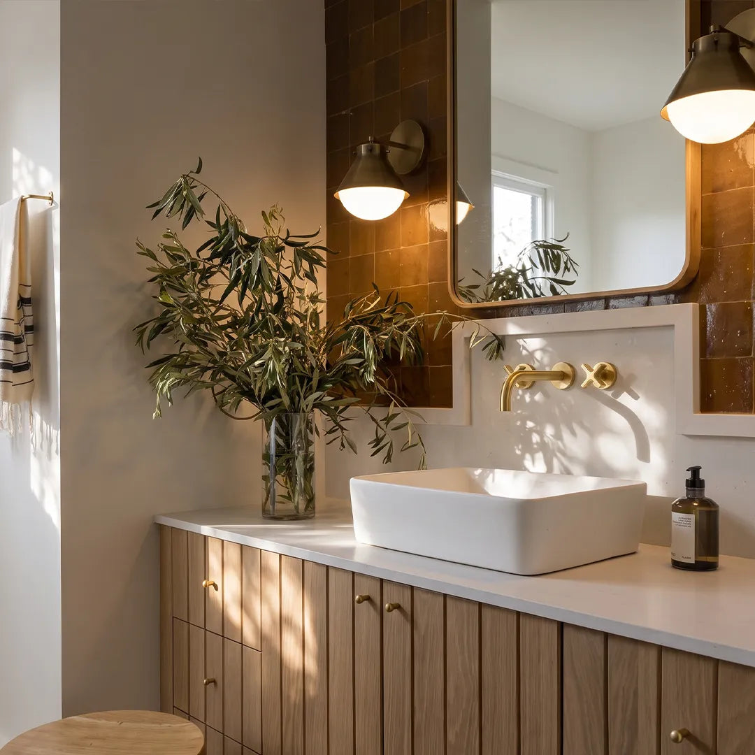 Metal and glass wall sconce mounted above a bathroom vanity mirror