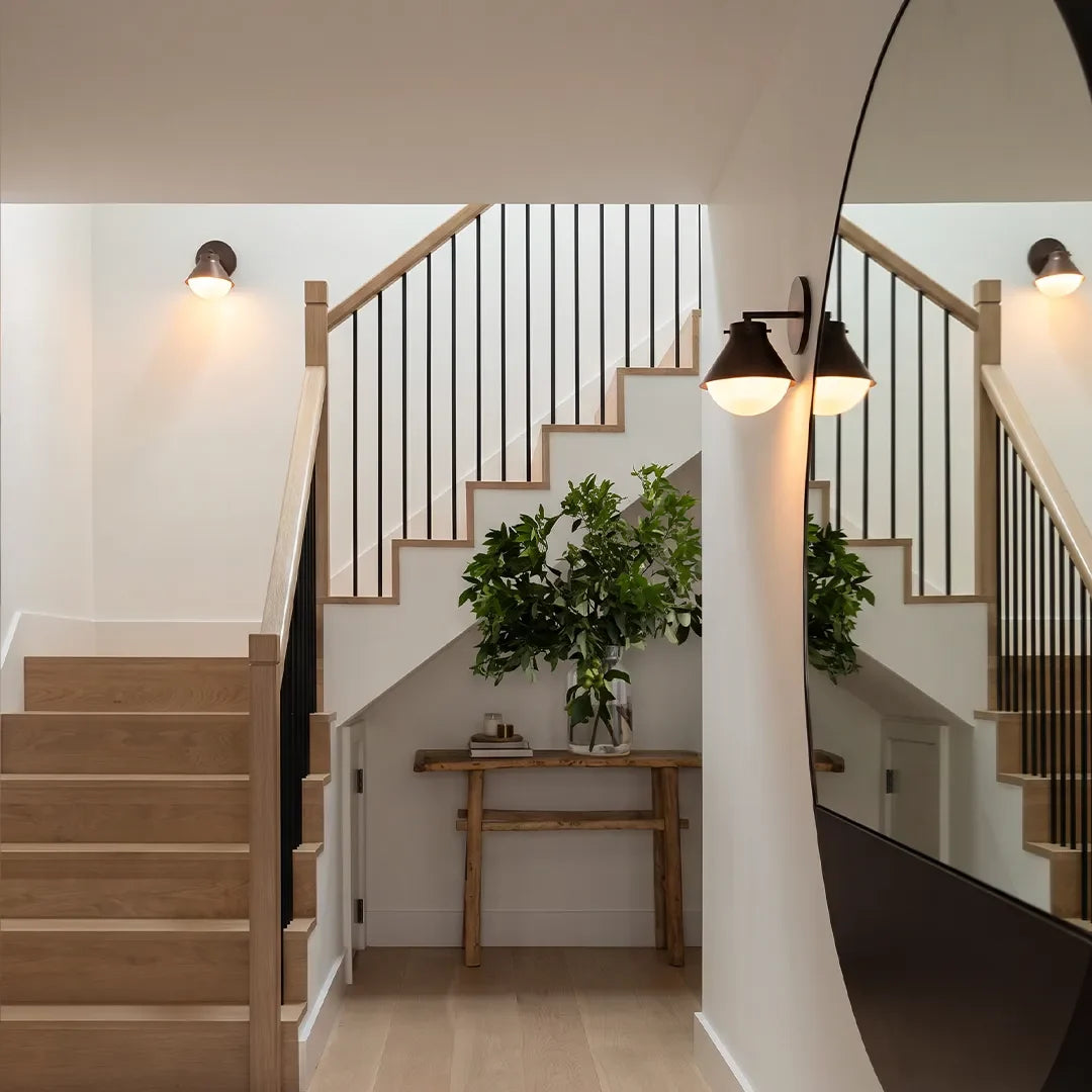 Metal wall sconce lights mounted along a staircase and hallway wall