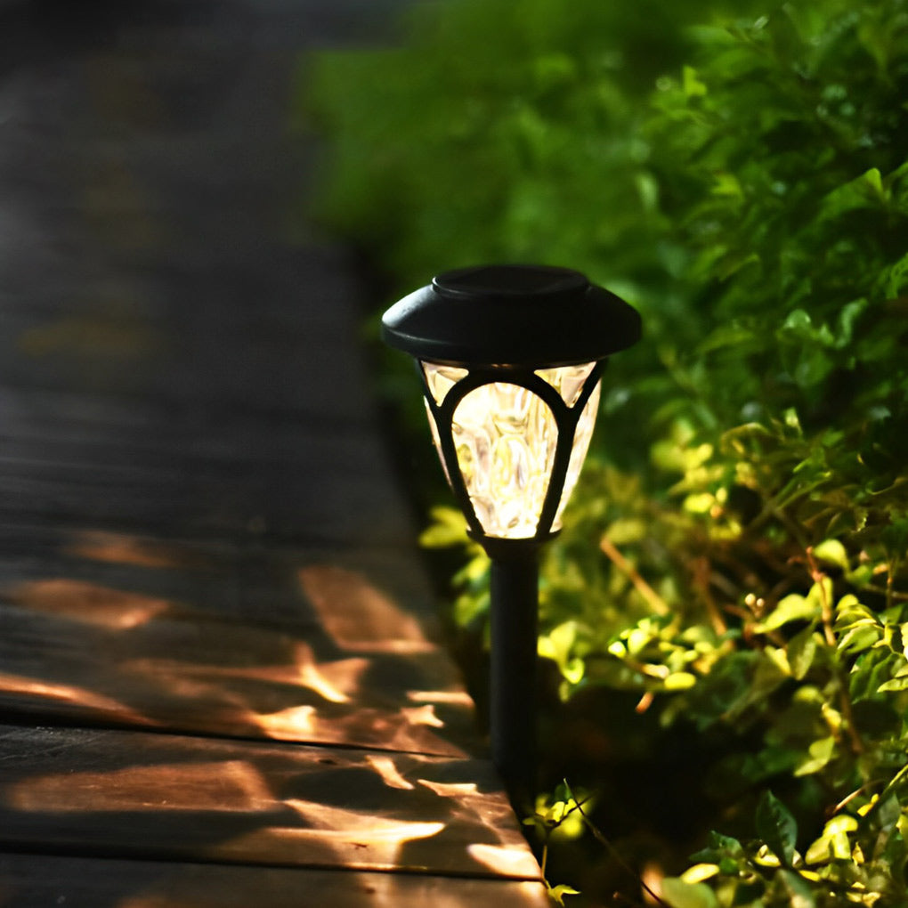 Solvara matte black solar garden light with frosted glass shown in daylight against green planting