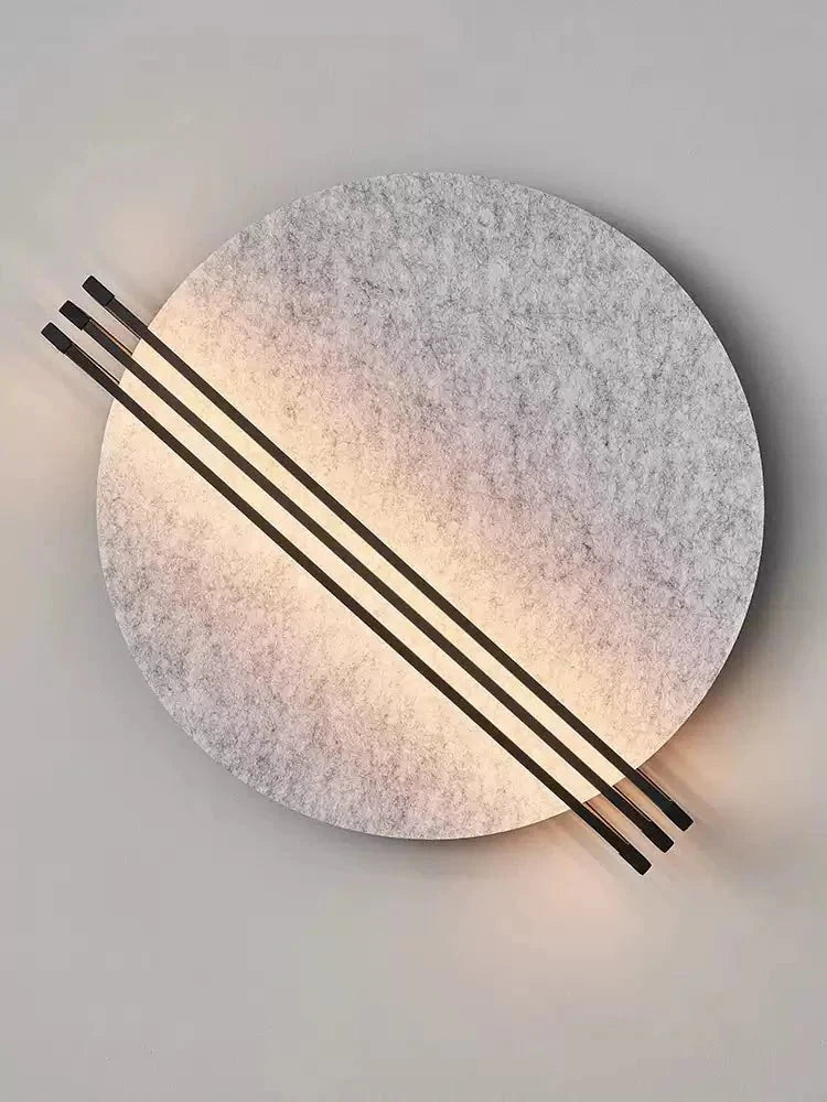 Vantara circular felt wall sconce in orange with black metal rod detail, mounted in a modern living room