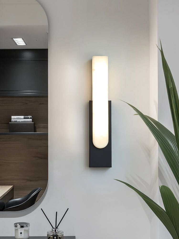 Iwara stone wall sconce lit at dusk showing warm diffused glow across a bedroom wall