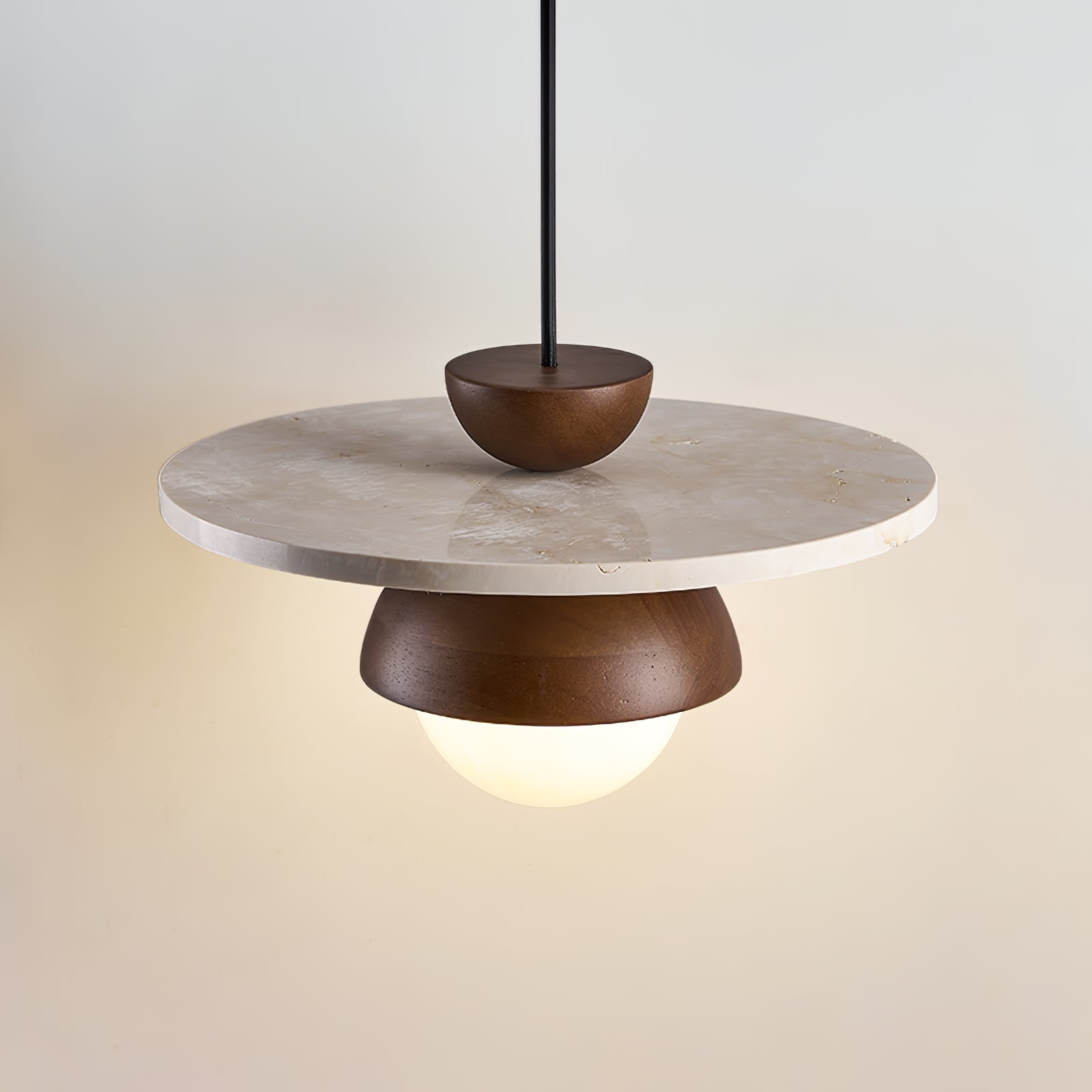 Arlo travertine and frosted glass pendant light hanging over a dining table, warm ambient glow