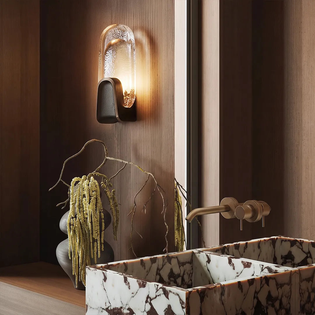 Oval smoked glass wall sconce above a bathroom sink, modern art deco brass wall light