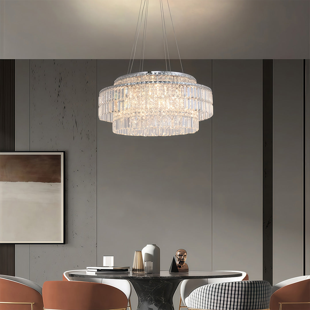 Crystal chandelier above dining table in a grey interior with marble accents, warm ambient light
