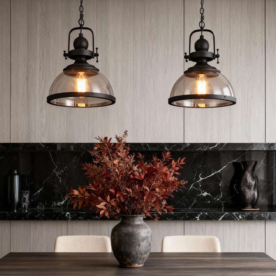 Clear glass pendant light over a modern kitchen island with black iron frame