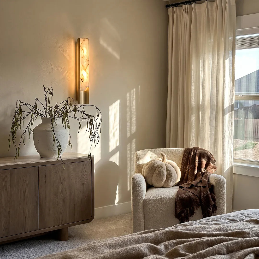 Niva marble wall sconce beside a reading corner, warm ambient stone lighting