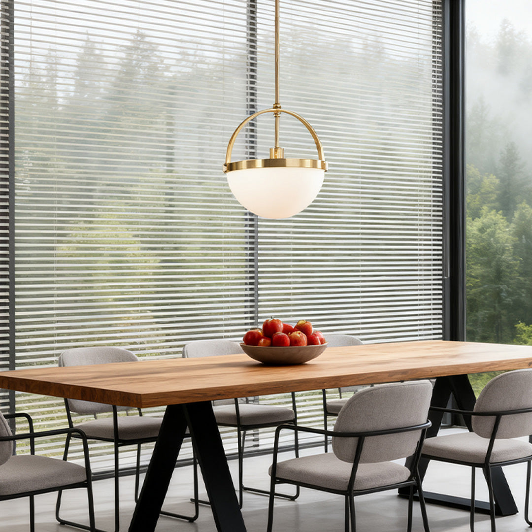 Contemporary gold copper pendant light with semi-globe frosted shade above a wooden dining table