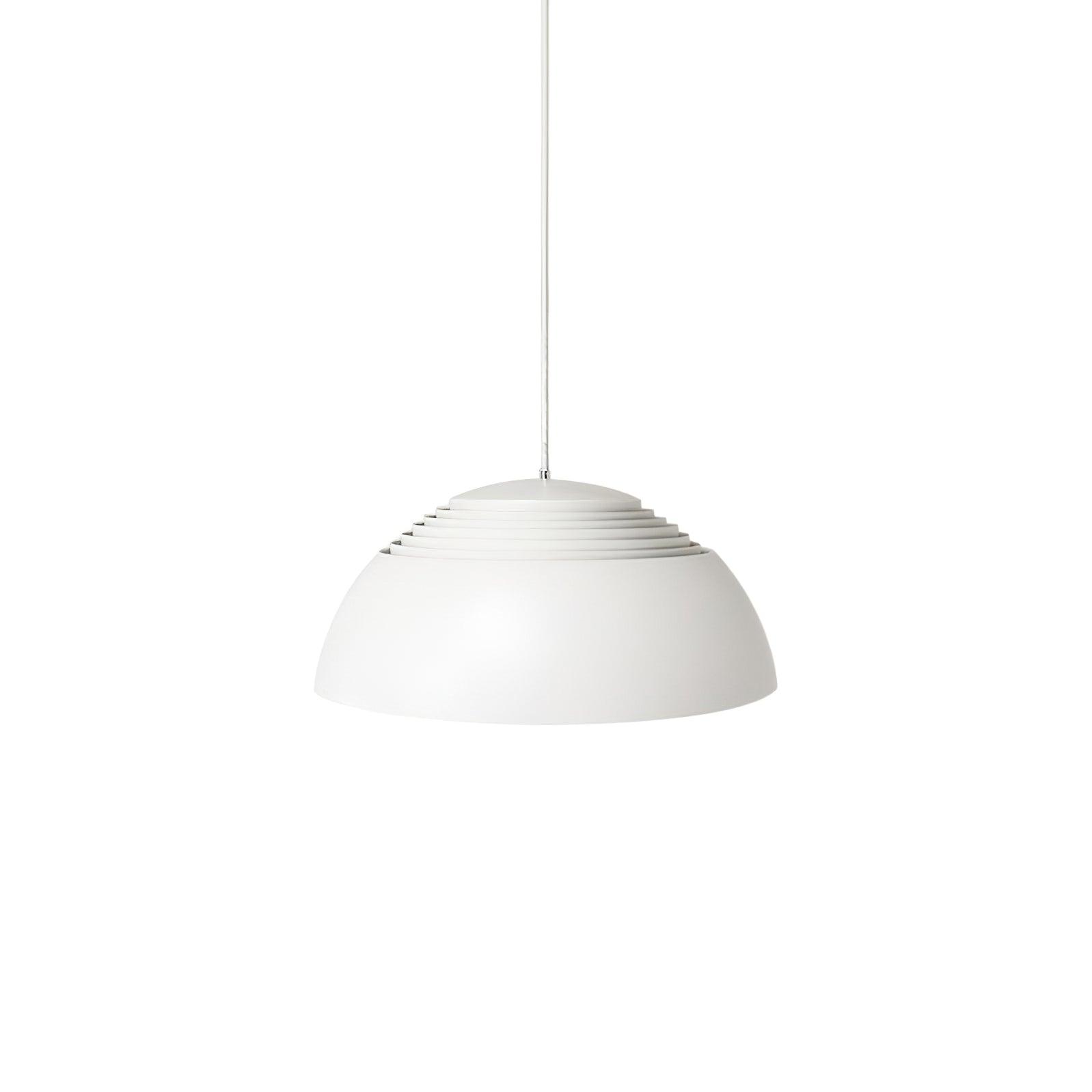 Vantara pendant light in matte white in a dining room with a concrete wall backdrop