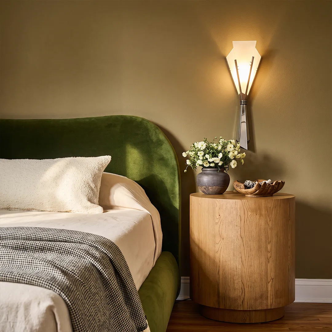 Niva marble wall sconce mounted beside a bedroom headboard with green upholstery