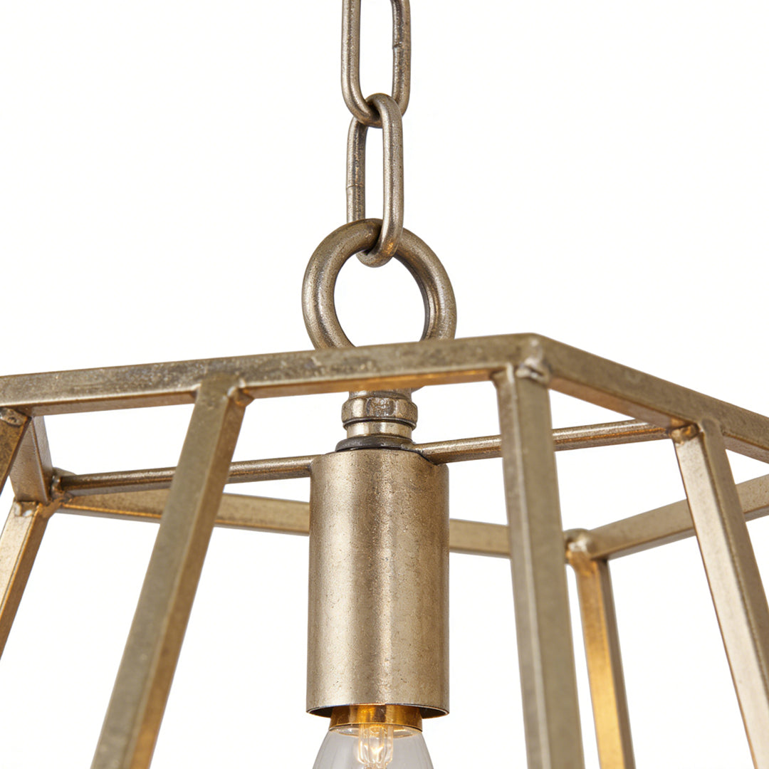 Gold pendant light suspended by chain, showing industrial-style cage frame detail