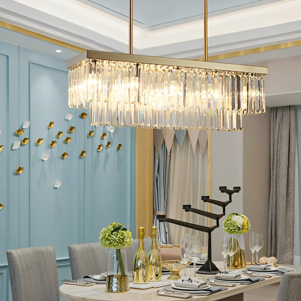 Rectangular gold chandelier with crystal shades above a minimalist dining table