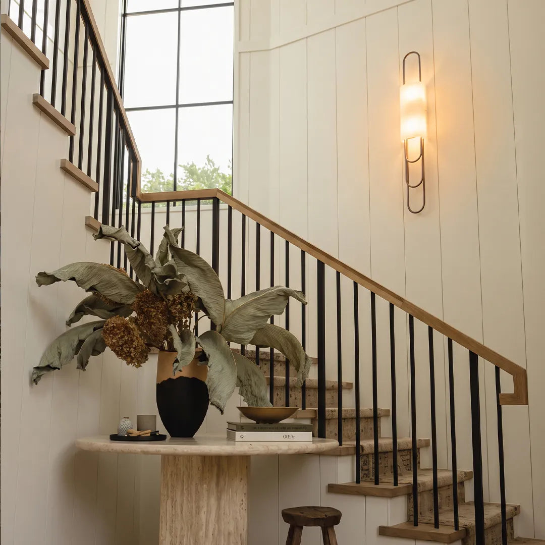 Niva modern marble wall sconce fitted on a staircase wall, showing warm ambient LED glow