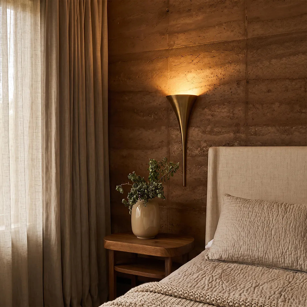Modern brass wall sconce used as bedside lighting in a contemporary bedroom