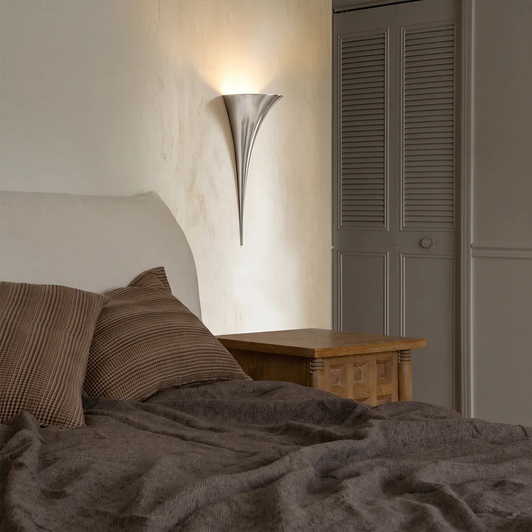Chrome finish brass wall sconce mounted in a contemporary bedroom