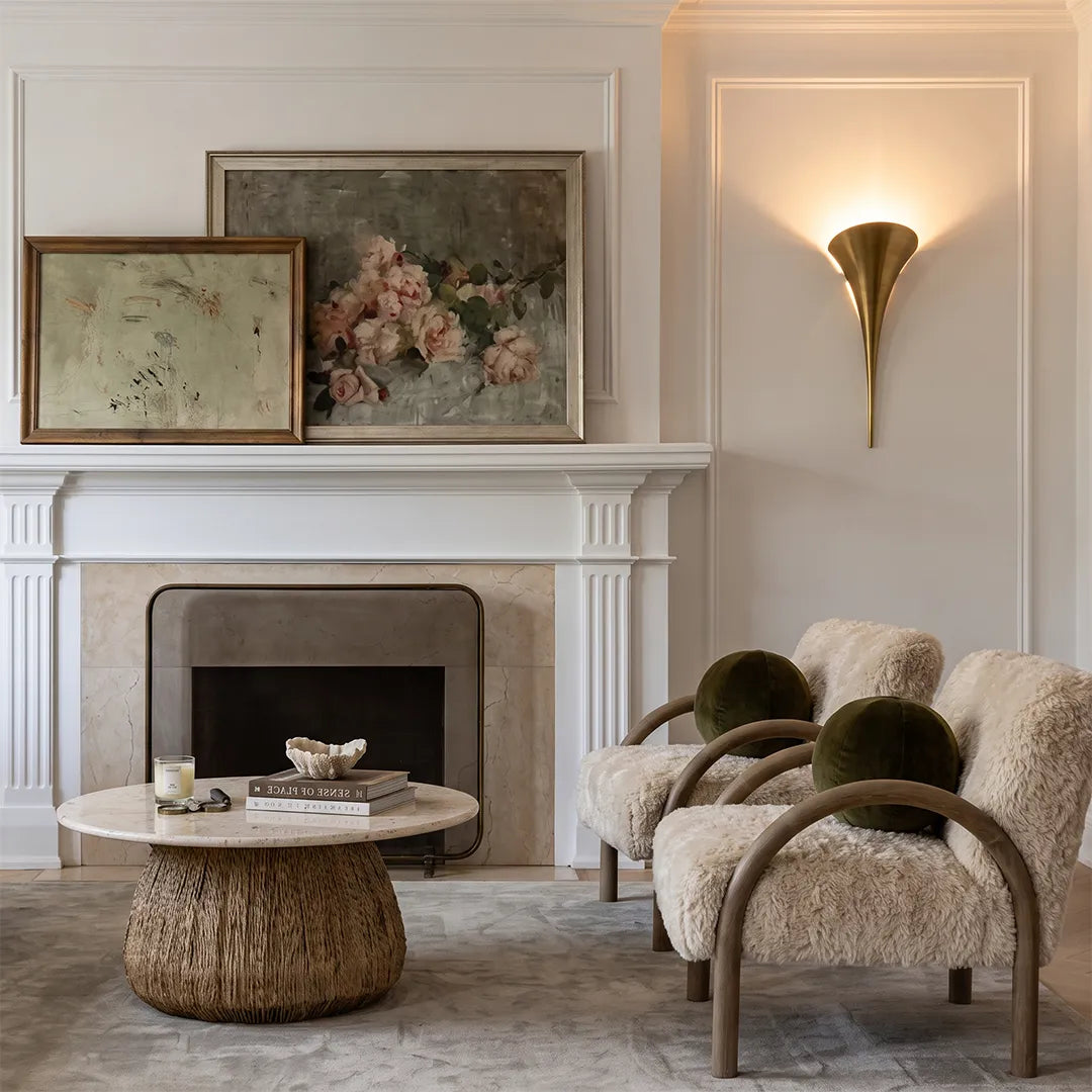 Brass wall sconce above a fireplace in a modern living room setting