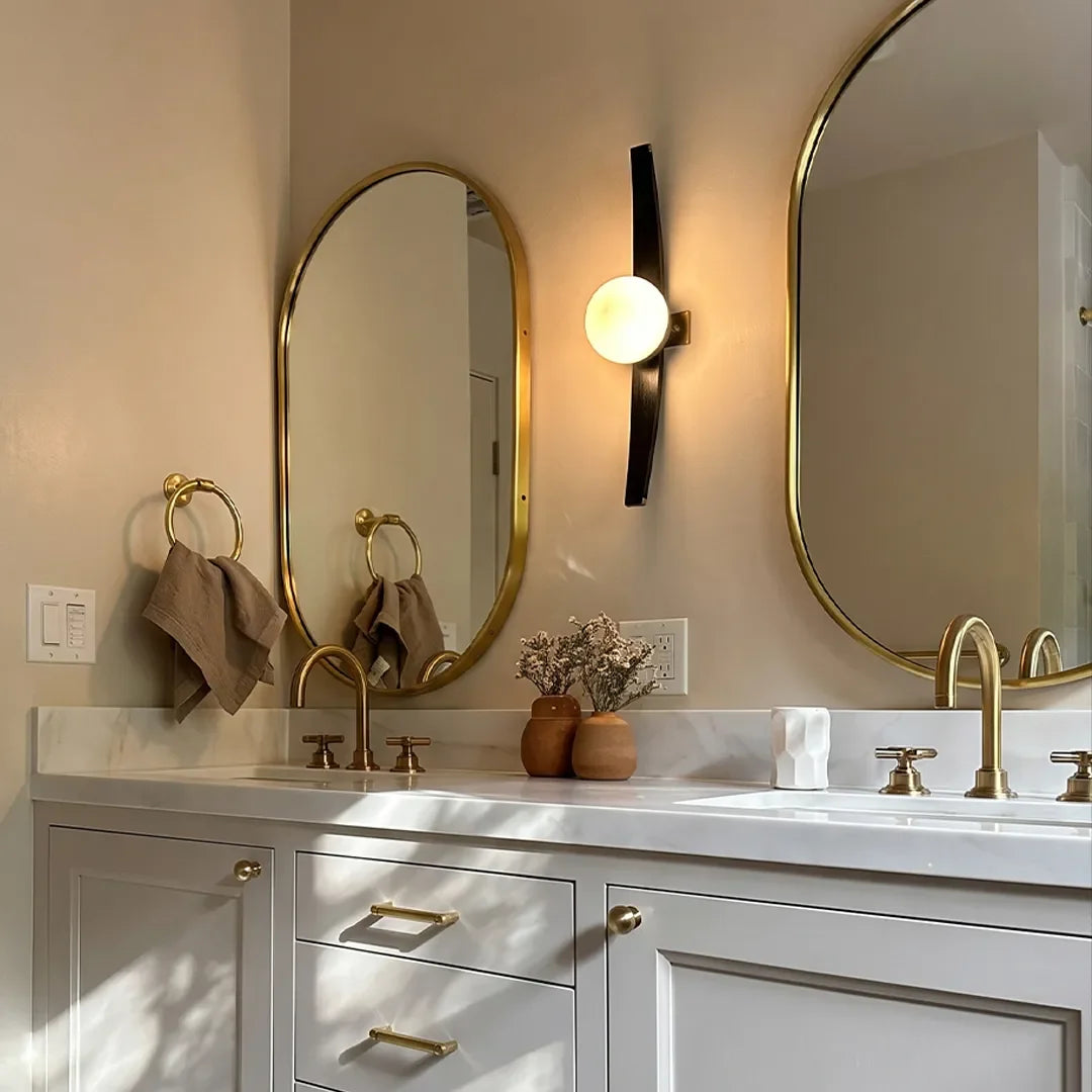 Niva modern globe wall sconce mounted beside a bathroom mirror, warm ambient light