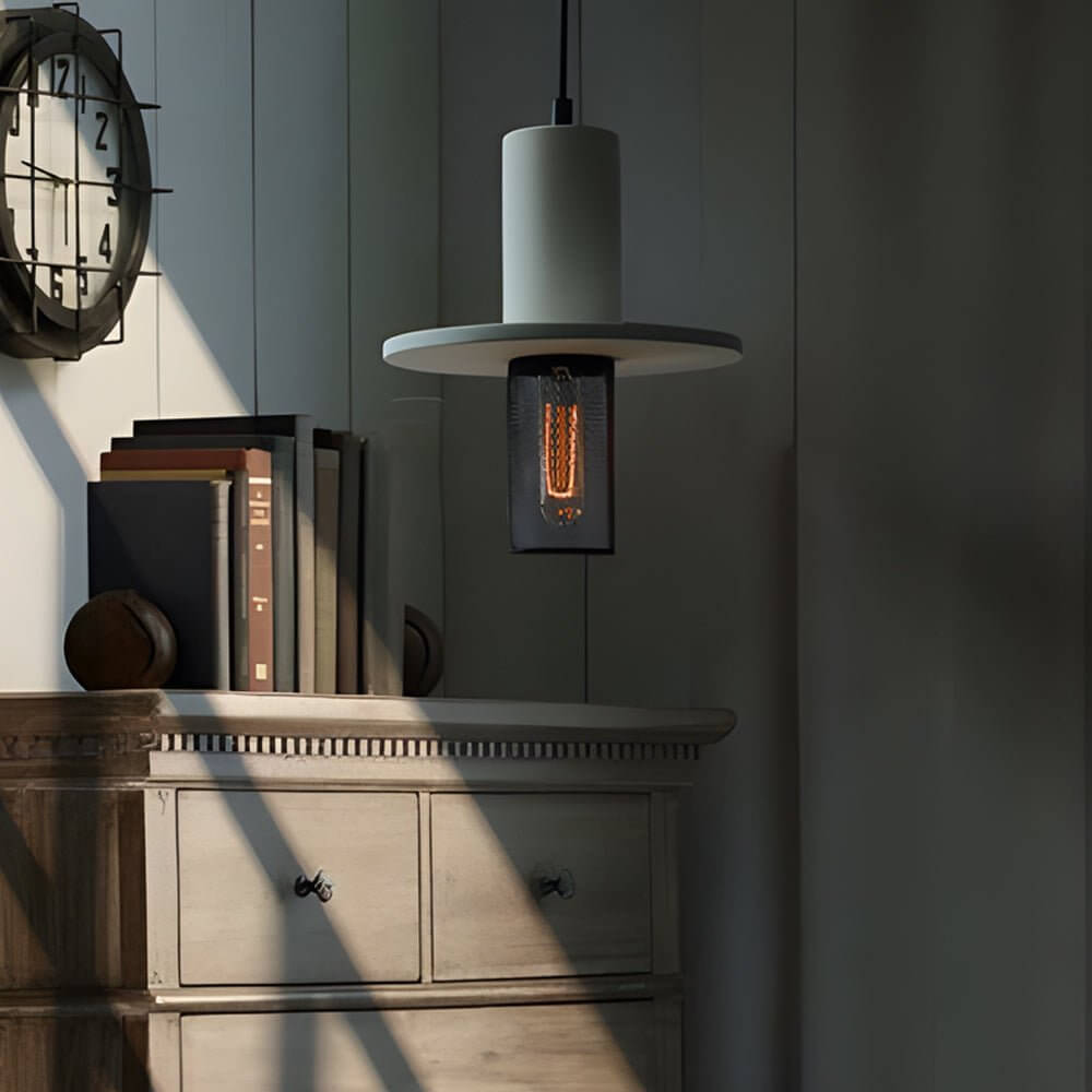 Aureon cylindrical cement pendant light above a dining table in a modern interior