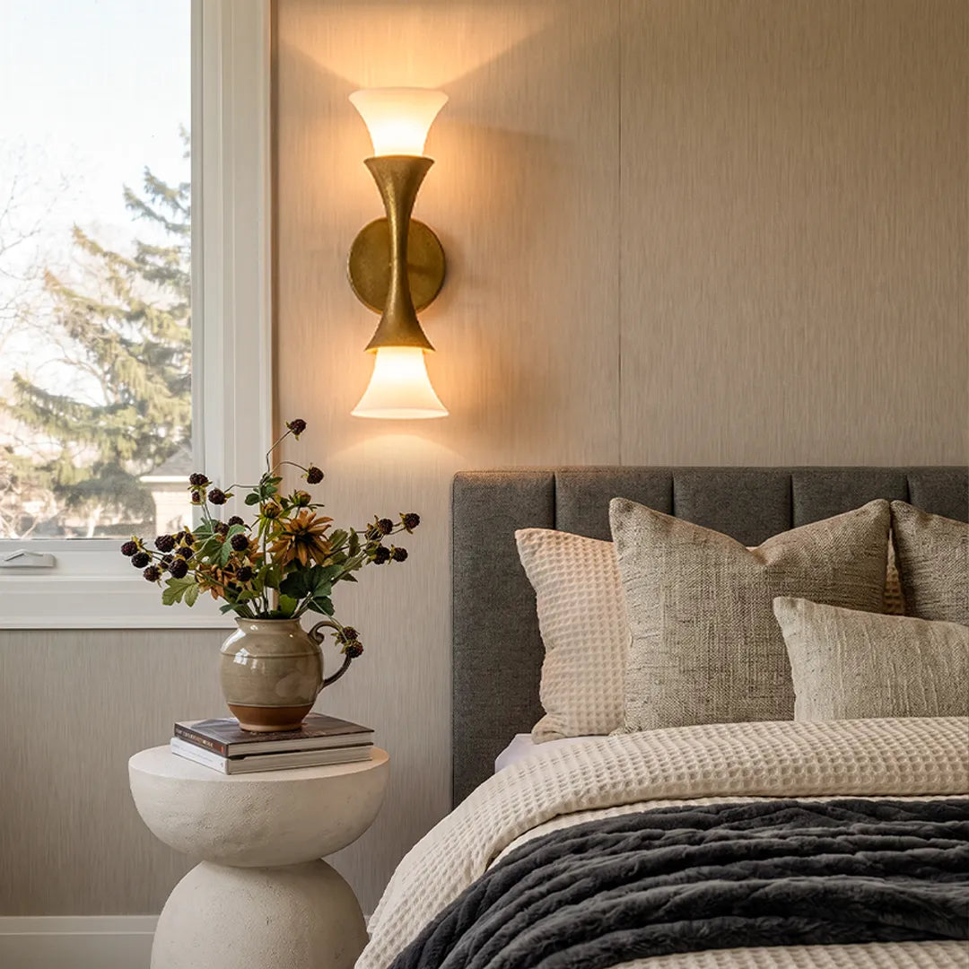 Niva antique brass wall sconce used as a bedside light in a neutral bedroom