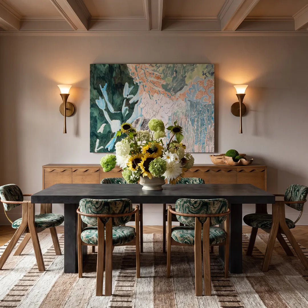 Niva brass wall sconce providing warm ambient lighting in a dining room