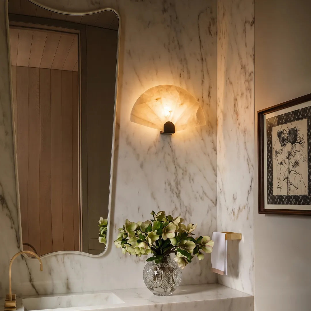 Marble wall sconce mounted beside a bathroom mirror, casting warm diffused light