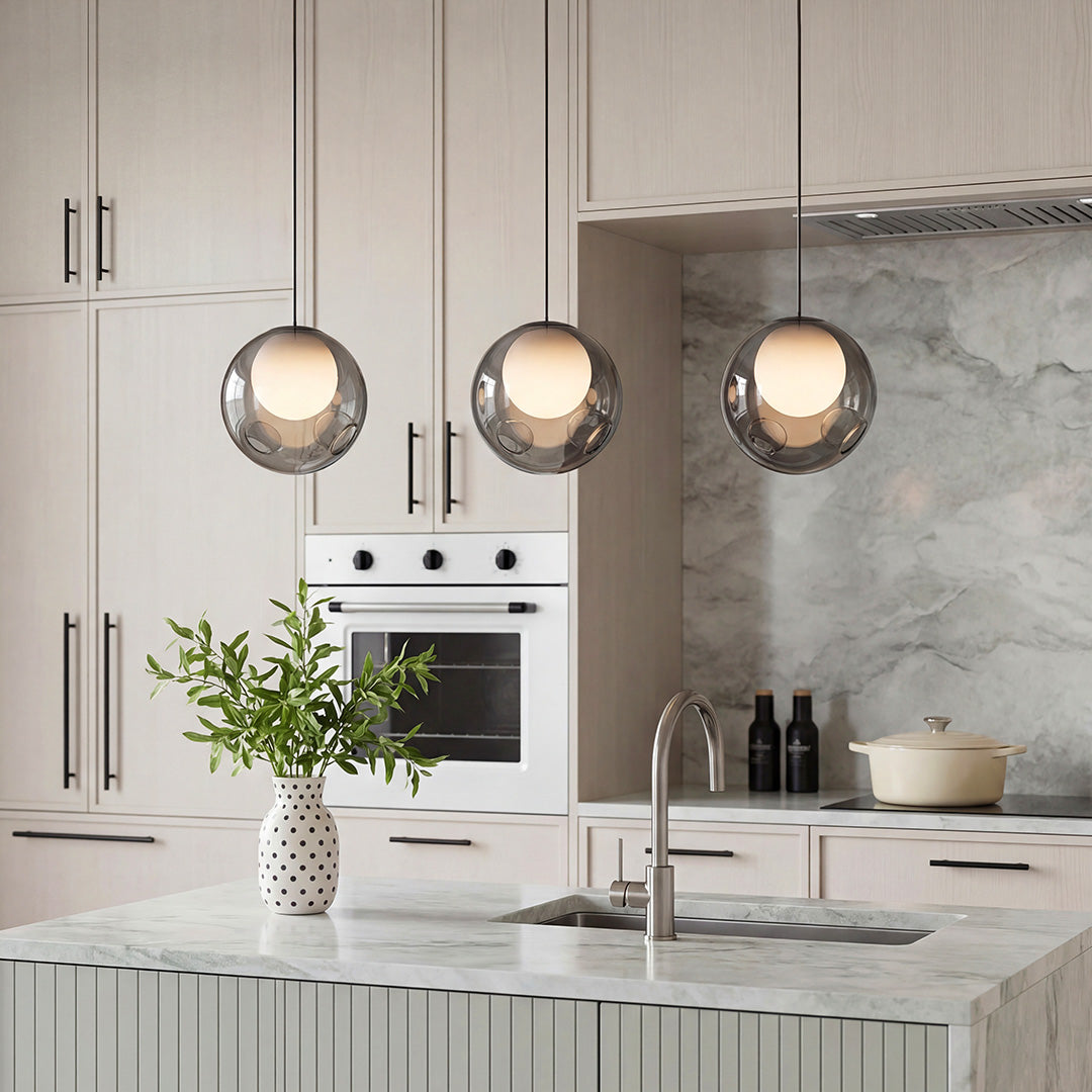 Three Aureon smoked glass globe pendant lights hung in a row above a kitchen island
