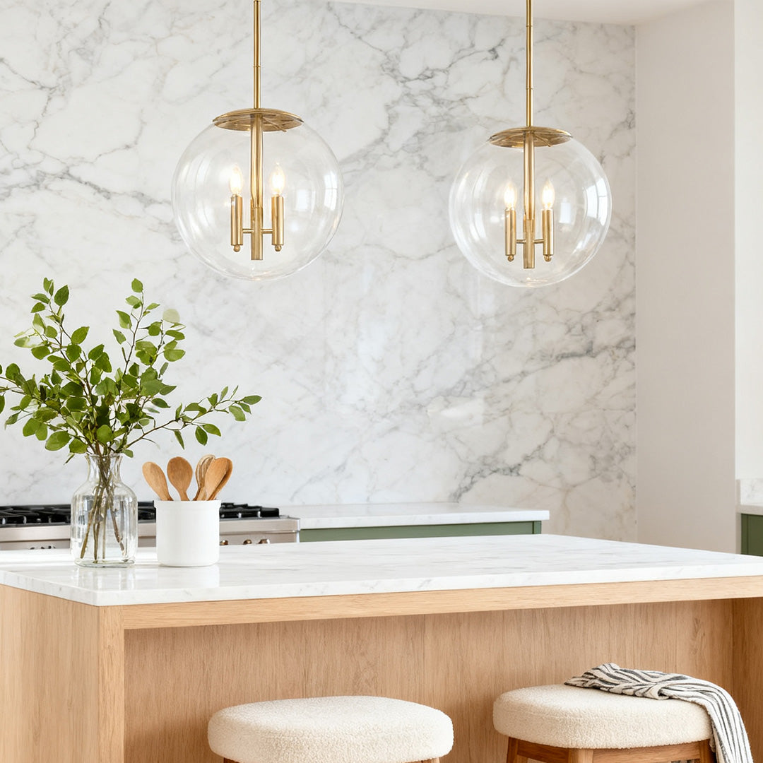 Clear globe pendant light with gold frame above a marble kitchen island