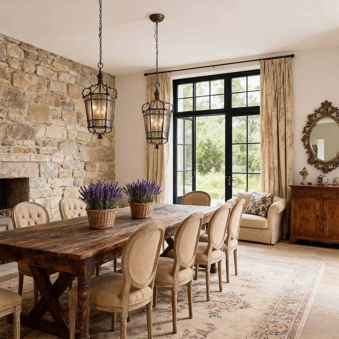 Gothic iron pendant light fixture above a long dining table beside a stone accent wall and large window