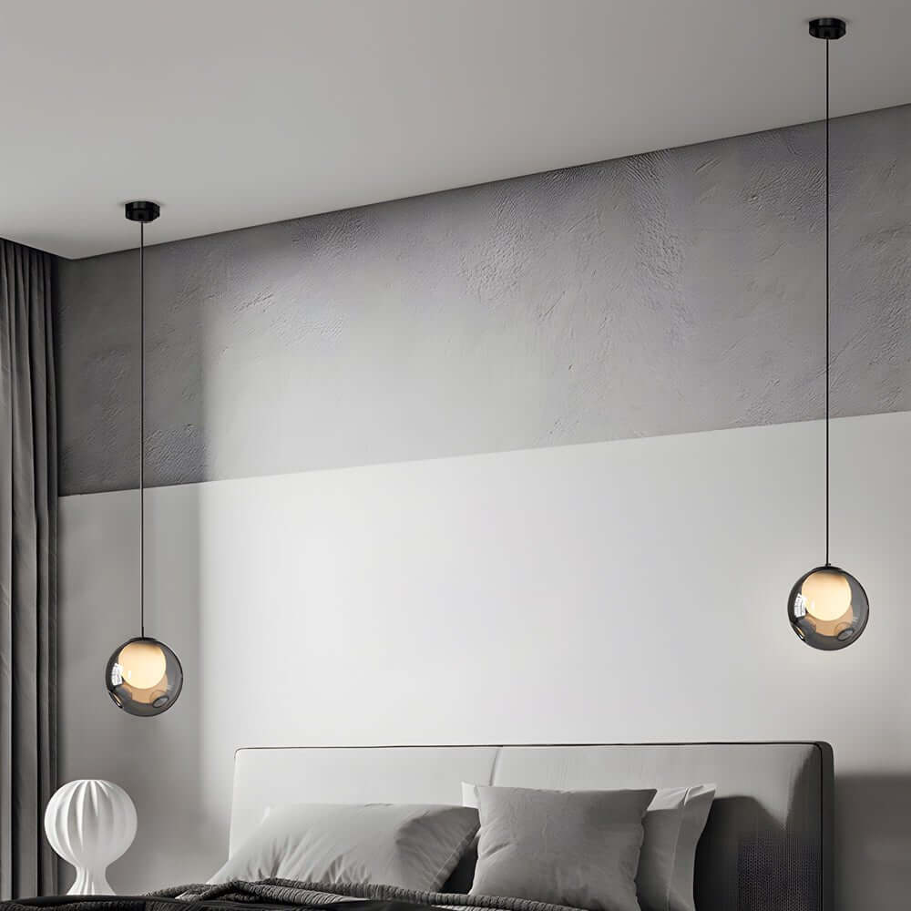 Symmetrical pair of Aureon smoked glass pendant lights above bedside tables in a modern bedroom