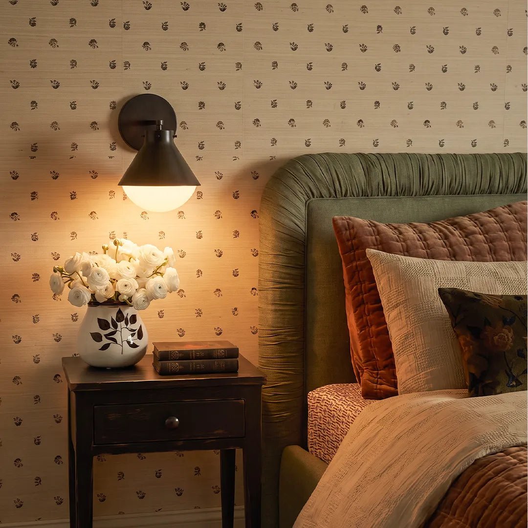 Dark-finish metal wall sconce with glass shade mounted in a modern bedroom setting