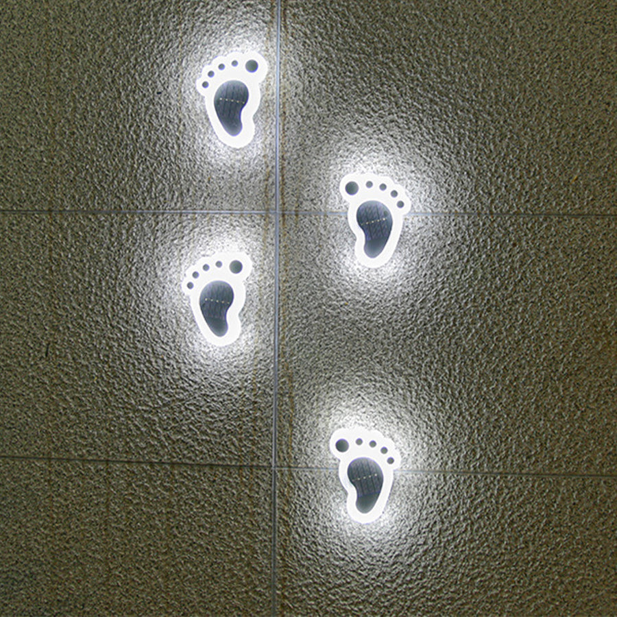 Solvara solar footprint garden path light set on a concrete walkway surrounded by ground-level planting