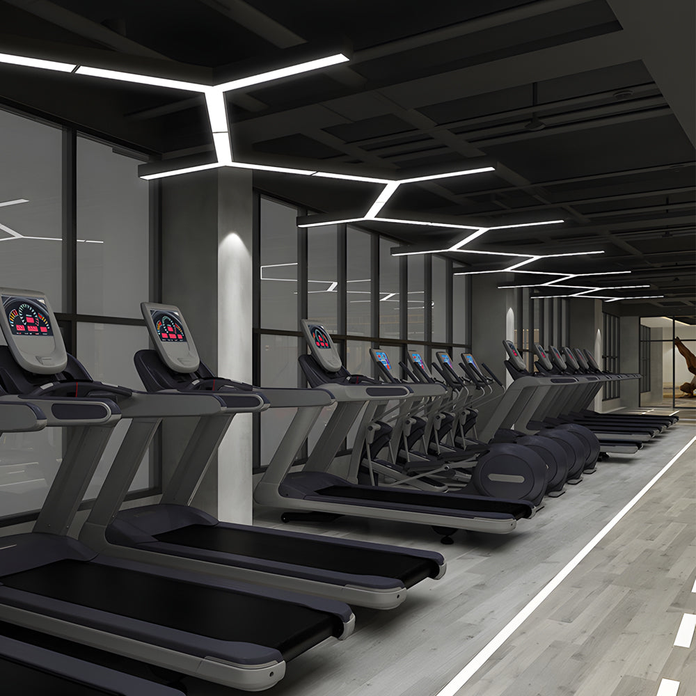 Y-shaped modular linear LED pendant light mounted on a gym ceiling